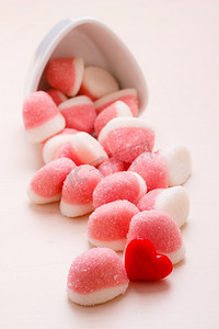 甜食糖果。粉红色果冻或棉花糖与糖在白色碗木桌上装饰有红心爱的象征