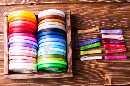 各种颜色的丝带线轴在老式木箱。木制桌子上的五颜六色的丝带线轴