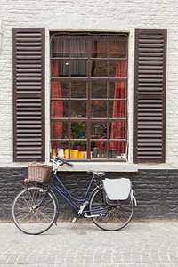 复古自行车站在旧窗户附近，比利时。老式自行车砖墙窗