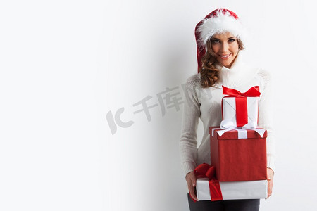 礼物一堆摄影照片_快乐的女人在圣诞帽与堆叠圣诞礼物。一堆礼物的女人