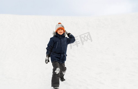 雪球摄影照片_童年，休闲和季节概念—快乐的小男孩扔雪球在冬天。快乐的男孩玩和扔雪球在冬天