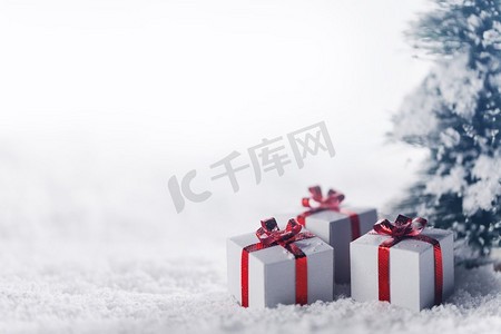 装饰圣诞礼物下的冷杉树雪地，背景与复制空间。树下雪中的礼品盒