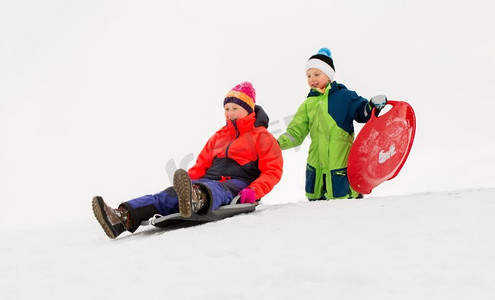 童年，雪橇和季节概念—快乐的小孩子在冬天滑下雪山的雪橇。冬天，孩子们在雪橇上滑下雪山