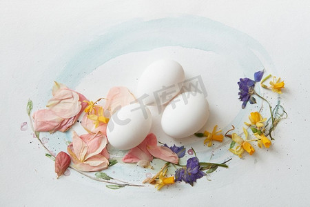 水彩画上的白色彩蛋，画有树叶和花朵。纸上的白色鸡蛋