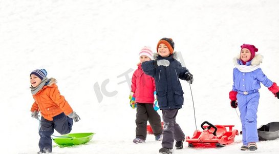 童年，雪橇和季节概念—一群快乐的小孩子在冬天雪橇。快乐的小孩子与雪橇在冬天