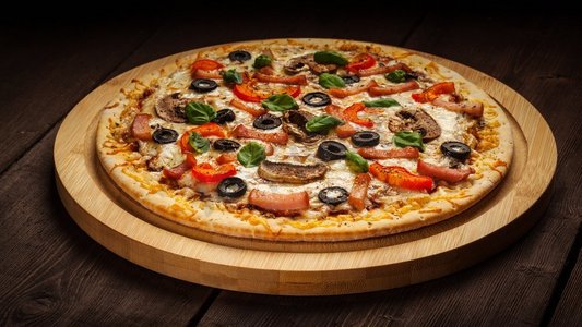 火腿披萨全景图，在旧桌子的木板上放着辣椒、蘑菇、橄榄和罗勒叶。木质背景火腿披萨
