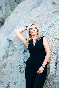 裤子裙子摄影照片_金发女郎在一个黑色裤子西装与蓝色眼睛在花岗岩采石场的背景从灰色瓦砾