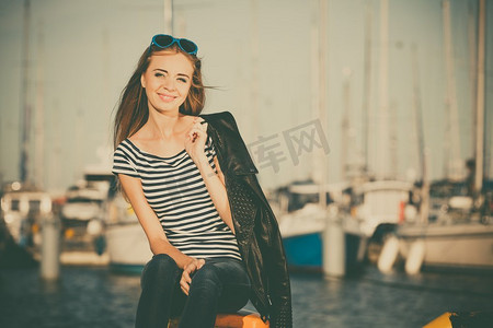 对峙摄影照片_旅游休闲与人的理念。戴着蓝色心形太阳镜的时尚金发女孩在码头与港口的游艇对峙