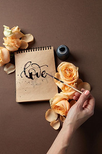 女孩写了一个祝贺爱的棕色背景与玫瑰。手用画笔写情书