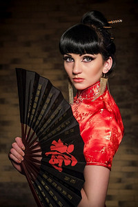 一个穿着红色日本丝绸连衣裙旗袍的女孩在黑暗的氛围中