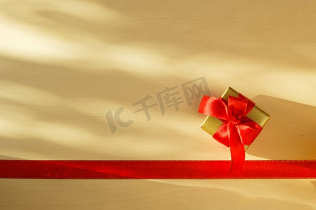 周年福礼摄影照片_假期，现在的概念。金色小盒子与礼品系装饰蝴蝶结和红丝带框架