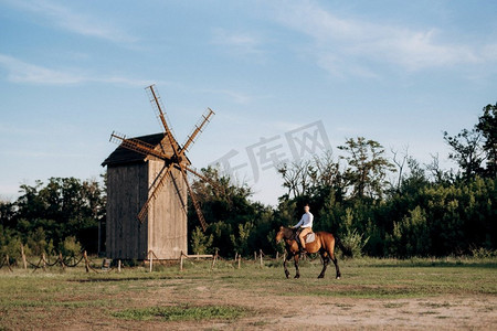一个穿着白衬衫的家伙在村子里和棕色的马散步