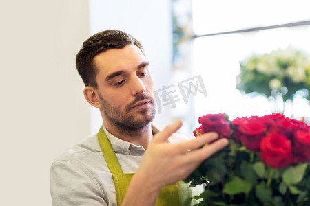 小玫瑰摄影照片_小企业，销售和花艺概念—花商或卖方设置红玫瑰在花店。在花店里摆放红玫瑰的花店或售货员