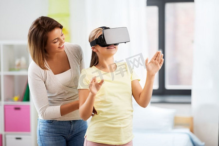 虚拟现实现实摄影照片_家庭、技术和虚拟现实概念--戴着VR眼镜的母女在家中玩耍。戴着VR眼镜的母女在家中玩耍