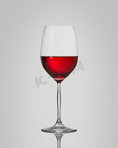 在灰色背景上孤立的玻璃杯中的红酒。隔离玻璃杯中的红酒