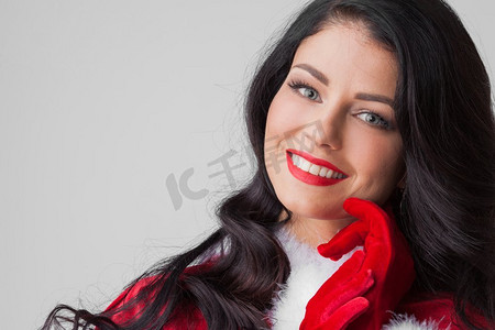 漂亮的Pin-Up风格的圣诞老人女孩穿着红色衣服，灰色背景。漂亮的圣诞老人女孩