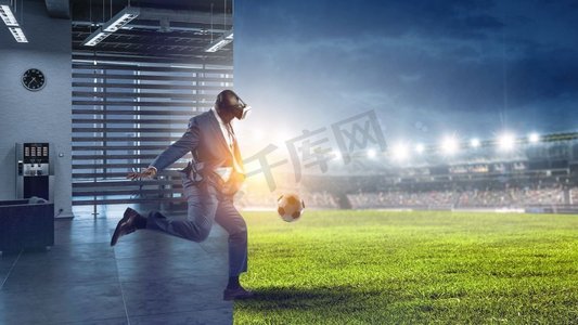 黑人男子与虚拟现实头盔踢足球，真实的房间vs imagesium体育场环境。黑人和虚拟现实足球比赛