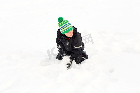 儿童玩雪摄影照片_童年，休闲，季节概念-快乐的小男孩在冬天玩雪。快乐的小男孩在冬天玩雪