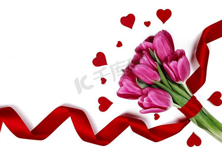 粉红色郁金香与丝带和心脏隔绝在白色背景情人节概念。郁金香和红心在白色