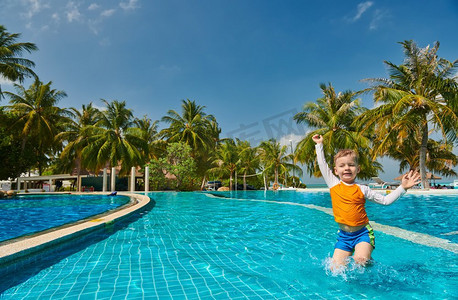 幼儿游泳摄影照片_三岁的蹒跚学步的男孩在度假村游泳池。暑假在马尔代夫度假。