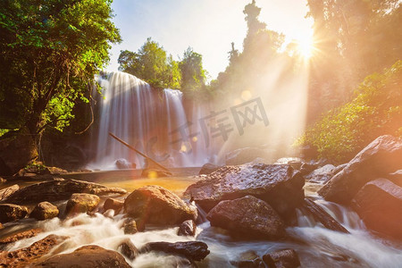 热带瀑布在上午与阳光在柬埔寨。镜头闪光和光线泄漏。早上的热带瀑布