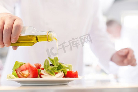 餐厅中段成熟厨师将油倒在盘子里的沙拉上