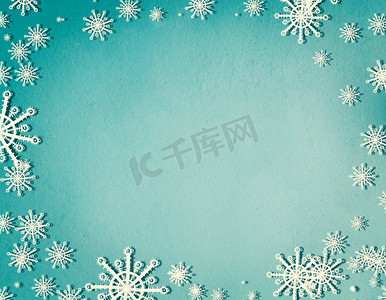 雪花框在蓝色绿松石背景上，带有复制空间，俯视。圣诞节和寒假的概念