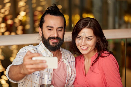 休闲、科技和人的概念-幸福的情侣在餐厅用智能手机自拍。一对情侣在餐厅用智能手机自拍