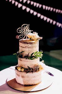 金色婚礼装饰摄影照片_婚礼装饰，在瀑布的背景下，蛋糕放在木凳上