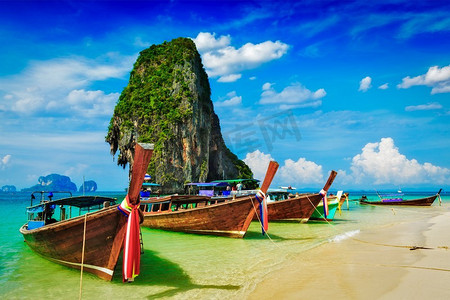 热带海滩上的长尾船与石灰岩岩石，甲米，泰国。泰国海滩上的长尾船