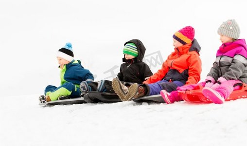 童年，雪橇和季节概念—一群快乐的小孩子在冬天滑雪橇。快乐的小孩子在冬天滑雪橇