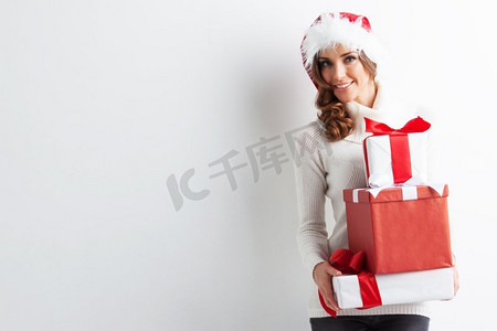 快乐的女人在圣诞帽与堆叠圣诞礼物。一堆礼物的女人
