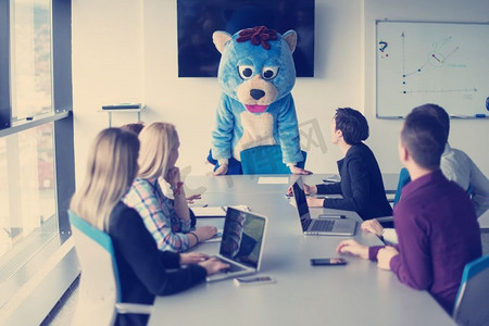 老板装扮成泰迪熊在现代公司办公室与商业人士玩耍