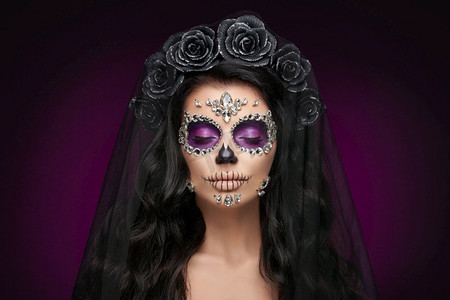 一个女人的肖像，在紫色的背景上涂着糖的骷髅妆。万圣节服装和化妆。卡拉维拉·卡特里娜的肖像