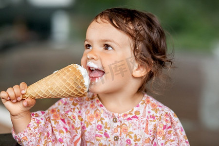 童年、休闲和人的概念--快乐的小女婴吃冰淇淋。快乐的小女婴吃着冰淇淋