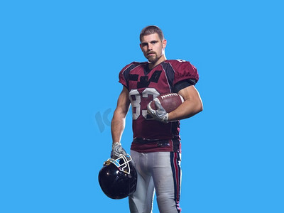 美国橄榄球运动员孤立在colorfull背景.一个强壮的肌肉美国橄榄球运动员的画象在五颜六色的背景隔绝