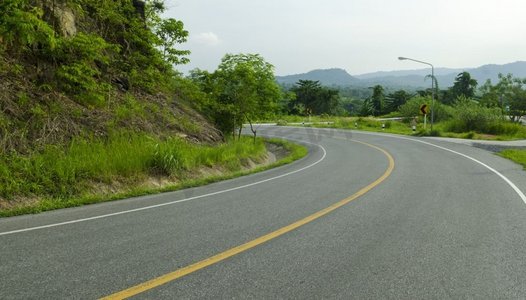 高速公路领域摄影照片_柏油路急弯沿着热带森林蜿蜒前行。