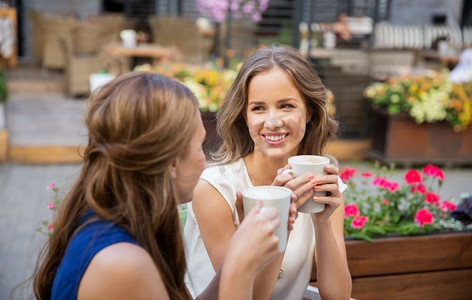 沟通，友谊和人的概念-快乐的年轻女子在户外咖啡馆喝咖啡。快乐的年轻女子在户外咖啡馆喝咖啡