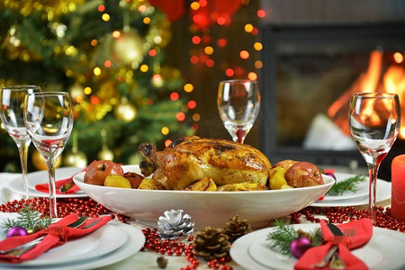 圣诞节晚餐摄影照片_圣诞树旁的鸡肉晚餐