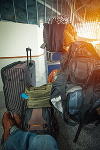 一个拿着很多行李的人坐在机场等飞机。对旅行的期待