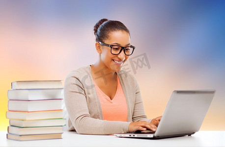 教育、学校和科技概念-微笑的非洲女学生，手持笔记本电脑和书籍。手持笔记本电脑和书籍的非洲留学生女孩