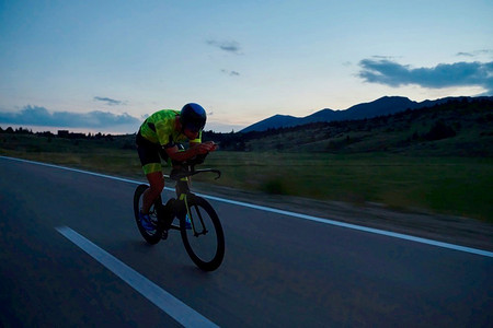 三项全能运动员骑专业赛车自行车在晚上锻炼在弯曲的乡村道路W