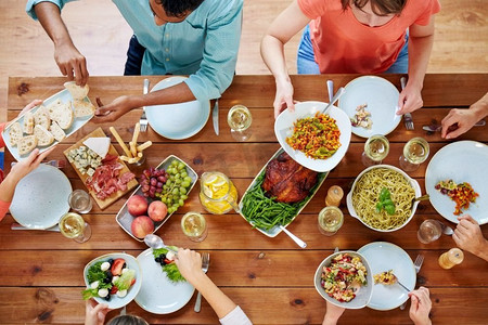感恩节，吃喝玩乐的概念-一群人在餐桌上吃晚餐，带着食物。一群人带着食物在餐桌上吃饭