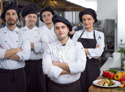 在餐厅的商业厨房里，集体厨师站在一起的肖像。群厨画像