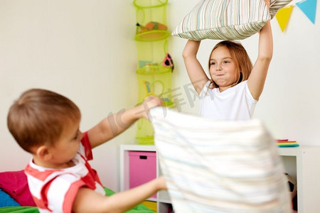 童年、休闲和人的概念-快乐的孩子们在家里靠着枕头玩耍和打架。孩子们在家里靠着枕头玩耍打架