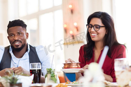 休闲，食物和人的概念—快乐的男人和女人在餐馆吃饭。快乐的男人和女人吃在餐馆