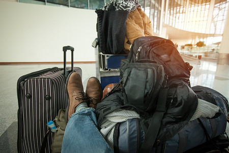 拿行李的人摄影照片_一个拿着很多行李的人坐在机场等飞机。对旅行的期待