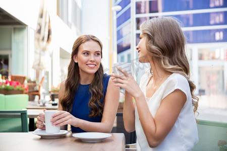 沟通和友谊的概念-微笑的年轻女子在街头咖啡馆喝咖啡。面带微笑的年轻女子在街头咖啡馆喝咖啡