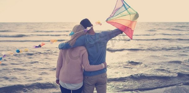 爱夫妇飞行风筝在海滩和具有乐趣在秋天天