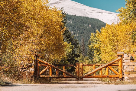秋天阳光明媚的一天，美国科罗拉多州未铺设的道路上，用原木做成的乡村大门。